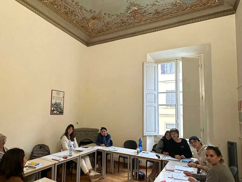 Teilnehmende lernen gemeinsam im Klassenzimmer mit historischem Deckenfresko und Tageslicht