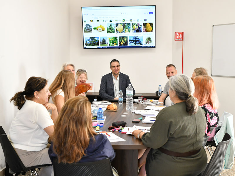 Lehrkraft unterrichtet eine kleine Gruppe Erwachsener mit visueller Präsentation