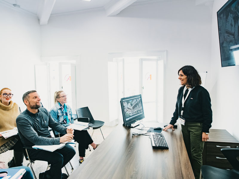 Lehrkraft erklärt Unterrichtsinhalte vor einer kleinen Gruppe im modernen Klassenraum