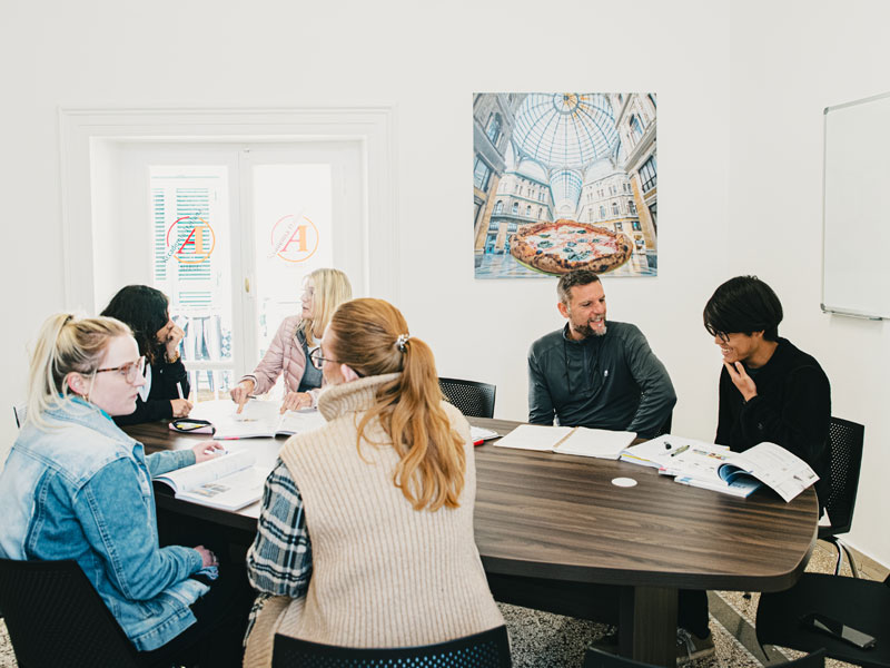 Kleine Gruppe Erwachsener arbeitet gemeinsam an Aufgaben im hellen Klassenzimmer