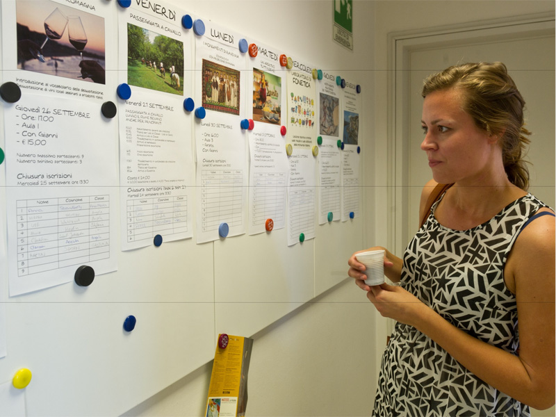 Frau liest aufmerksam eine Infotafel mit Kurs- und Freizeitangeboten in der Sprachschule