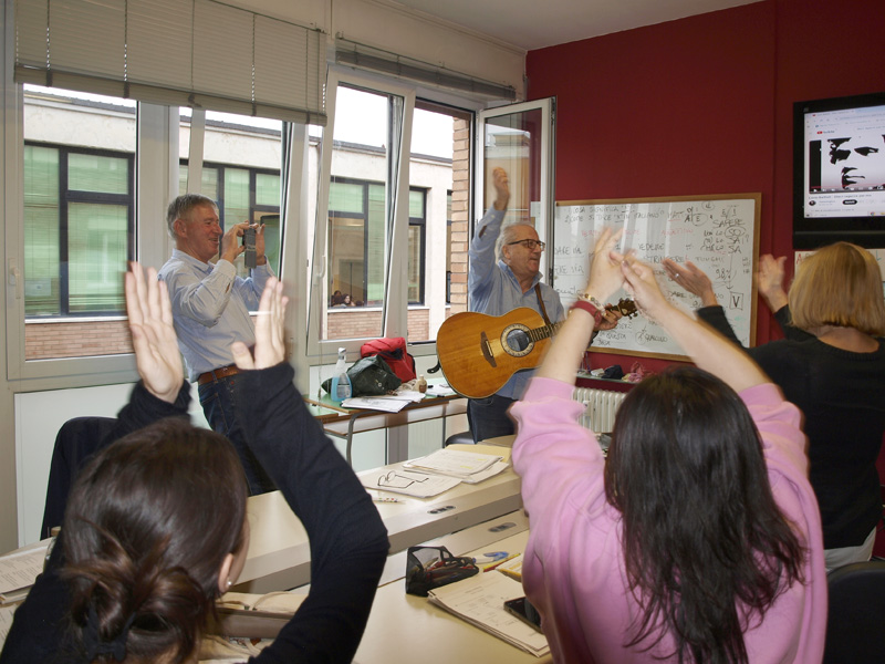 Lehrer spielt Gitarre und animiert Sprachschüler zum Mitmachen im Unterricht