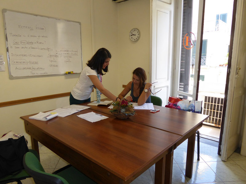 Lehrerin erklärt Unterrichtsinhalte im Einzelunterricht an einem großen Holztisch