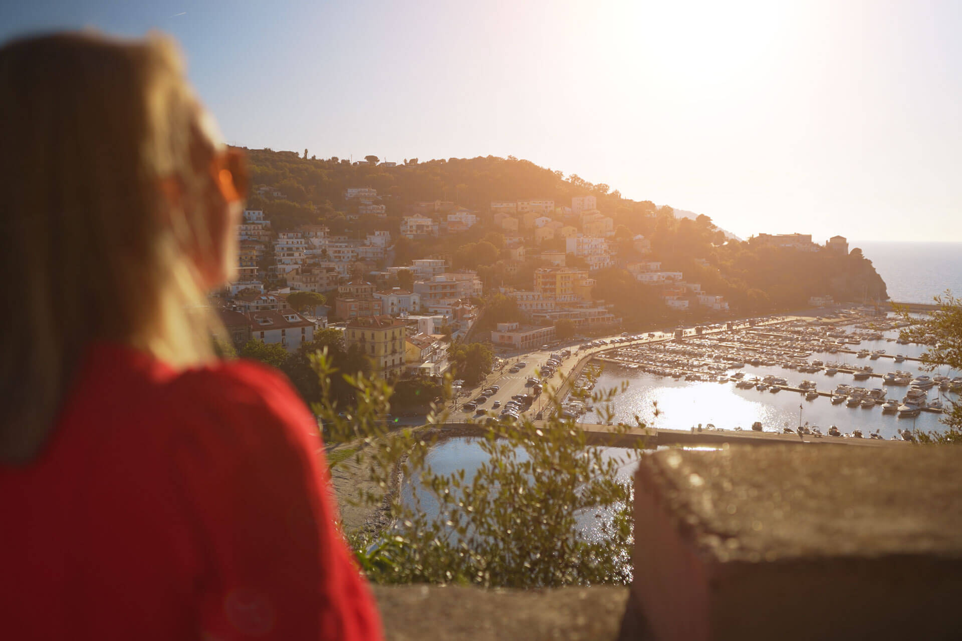 Frau blickt bei Sonnenuntergang auf den Hafen und die Altstadt von Salerno