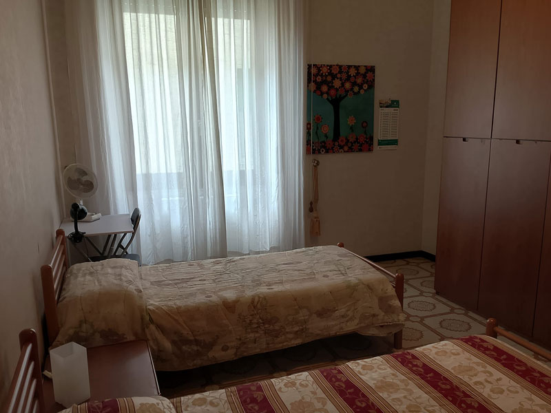 Zweibettzimmer mit Einzelbetten, Kleiderschrank und Fenster in einem Apartment..