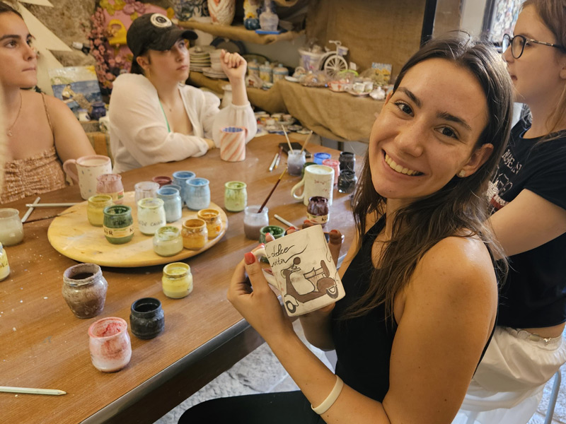 Teilnehmerin präsentiert stolz eine bemalte Keramik während eines Kunstworkshops