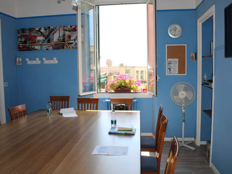 Heller Klassenraum der Sprachschule mit blau gestrichenen Wänden und offenem Fenster mit Blumenkasten