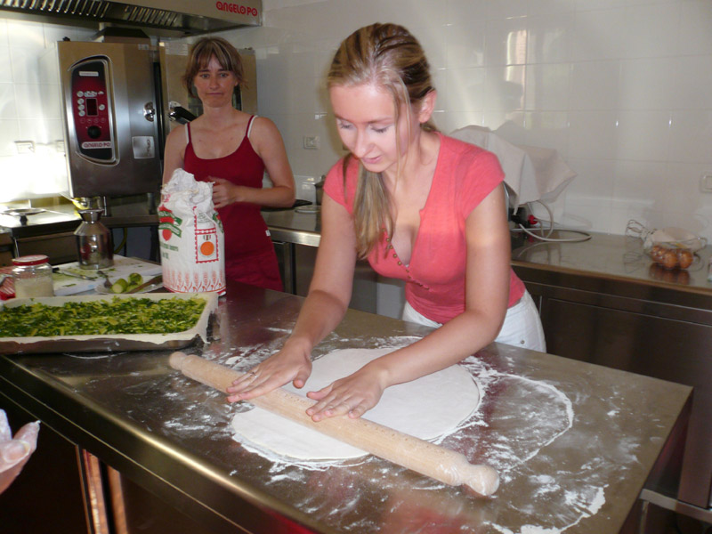 Teilnehmerin rollt Teig für ein italienisches Gericht während eines Kochkurses aus