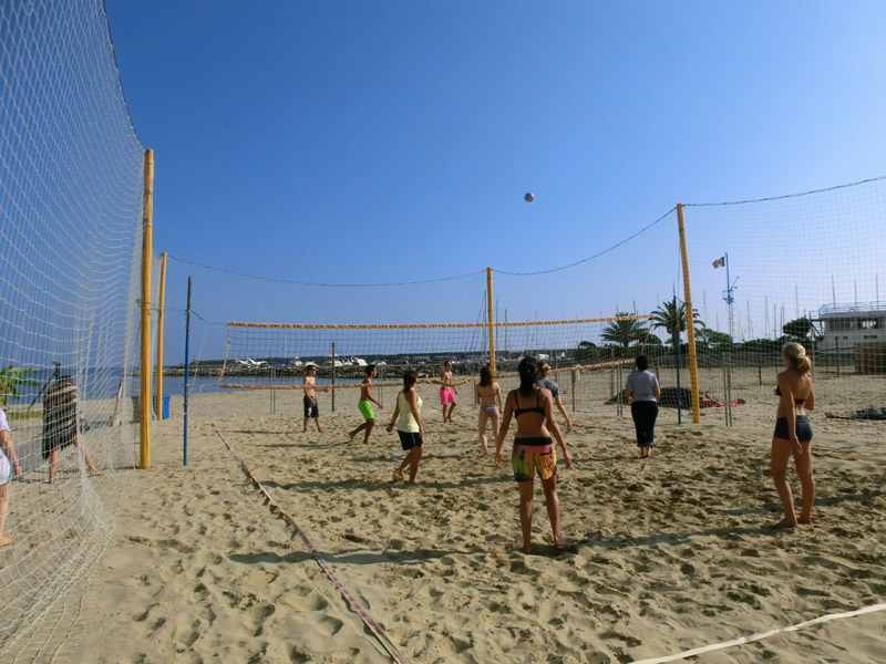 Jugendliche spielen Beachvolleyball am Sandstrand von Sanremo bei sonnigem Wetter