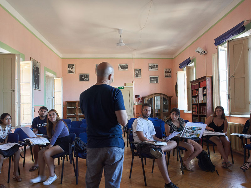 Lehrer unterrichtet eine Gruppe Erwachsener in einem hellen Klassenzimmer der Sprachschule Siena