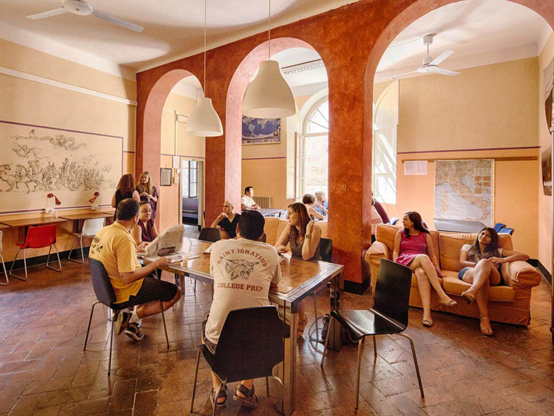 Sprachschüler entspannen und unterhalten sich im gemütlichen Aufenthaltsraum der Dante Alighieri Sprachschule Siena
