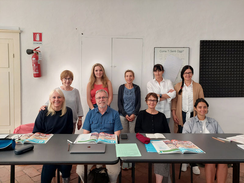 Erwachsene Sprachschüler posieren gemeinsam im Klassenzimmer der Dante Alighieri Sprachschule Siena