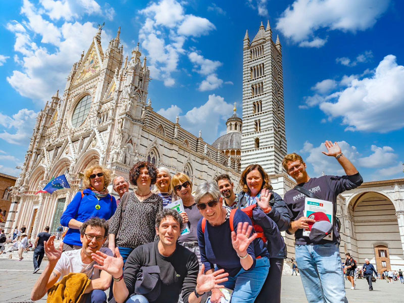 Gruppe von Sprachschülern besucht den berühmten Dom von Siena und winkt in die Kamera