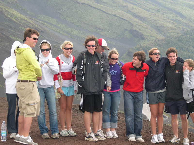 Gruppe von Sprachschülern steht lachend auf einem Berghang bei einem Ausflug auf den Ätna