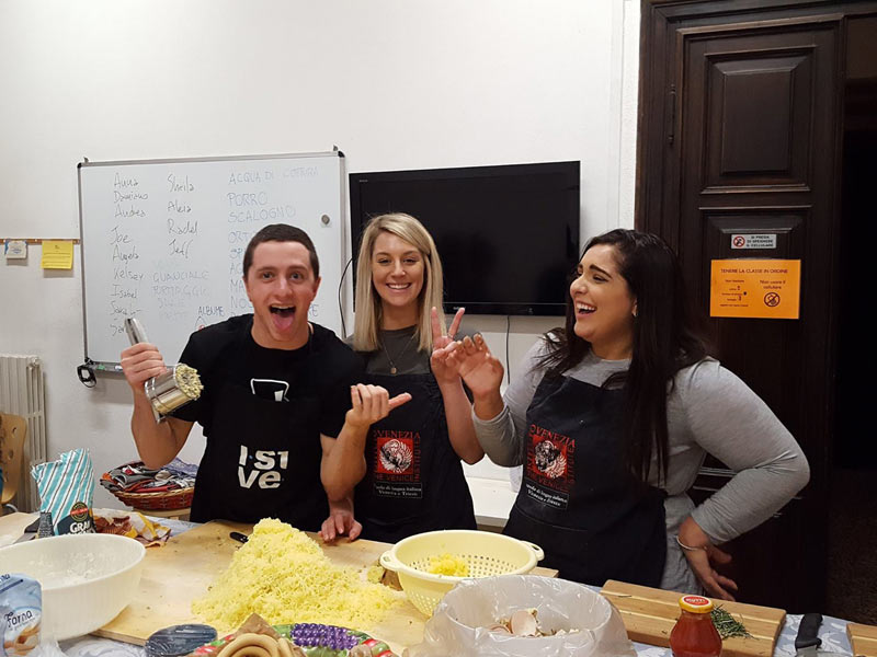 Drei Teilnehmende haben sichtlich Spaß beim gemeinsamen Kochen im Unterrichtsraum