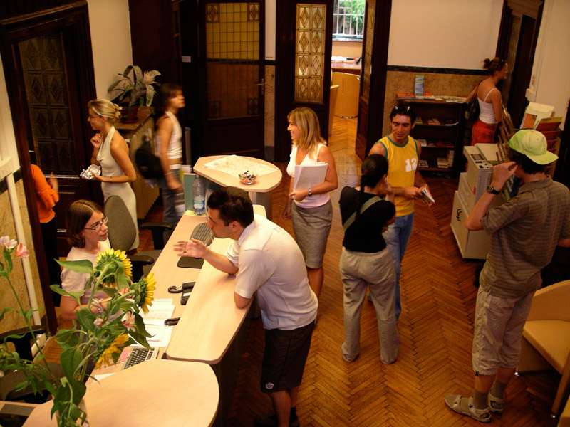 Empfangsbereich der Piccola Università Italiana Triest mit Lernenden und Mitarbeitenden im Gespräch