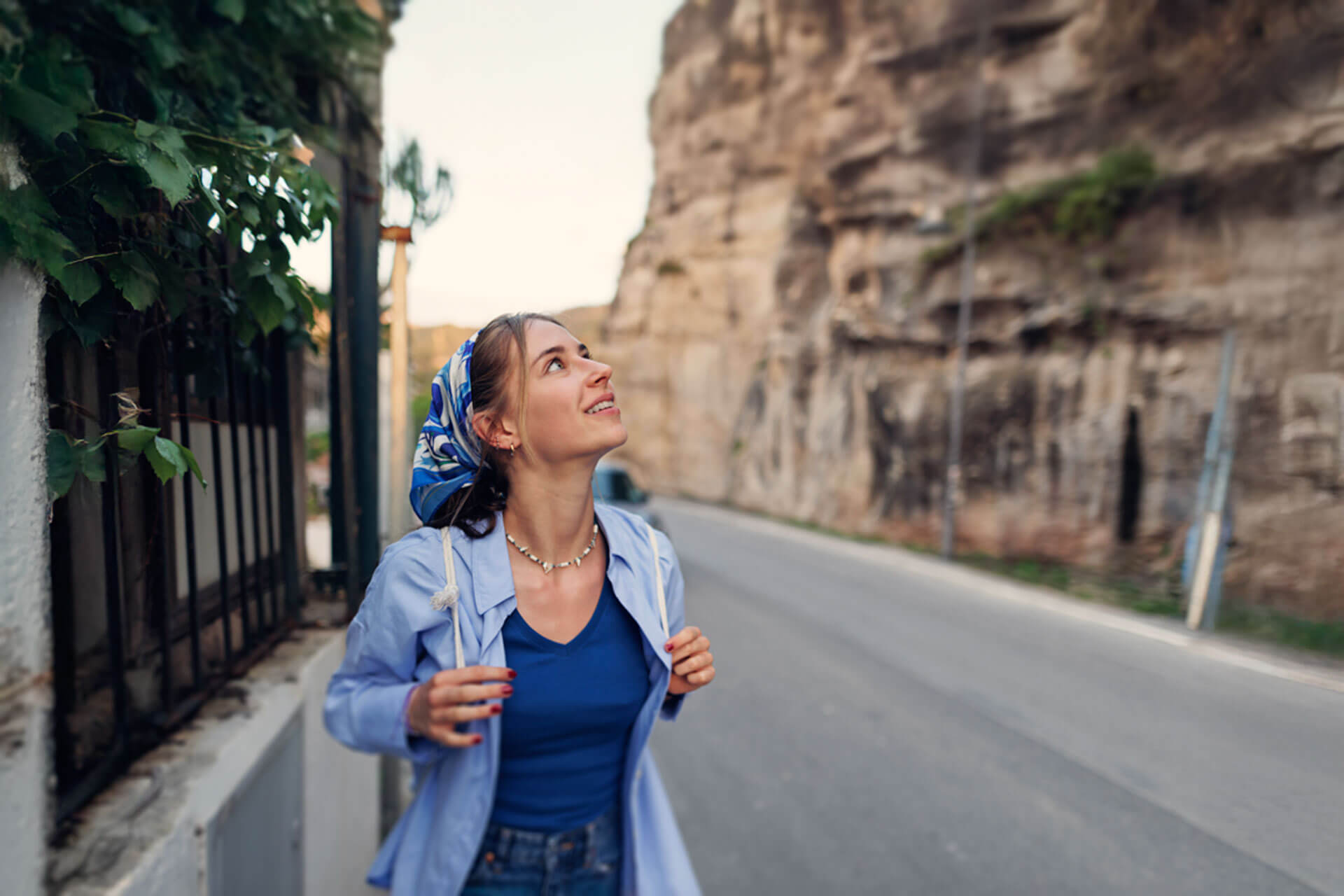 Junge Frau mit Kopftuch spaziert durch die Altstadt von Tropea und blickt neugierig nach oben