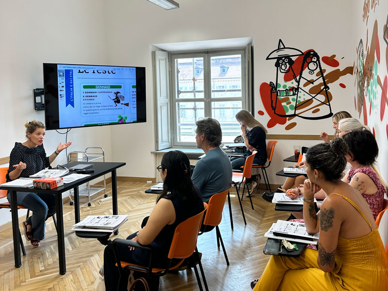 Lehrerin unterrichtet eine kleine Gruppe von Sprachschülern mithilfe einer digitalen Präsentation