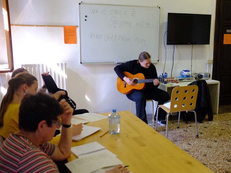 Lehrerin spielt Gitarre während des Unterrichts im Istituto Venezia und schafft eine lebendige Lernatmosphäre