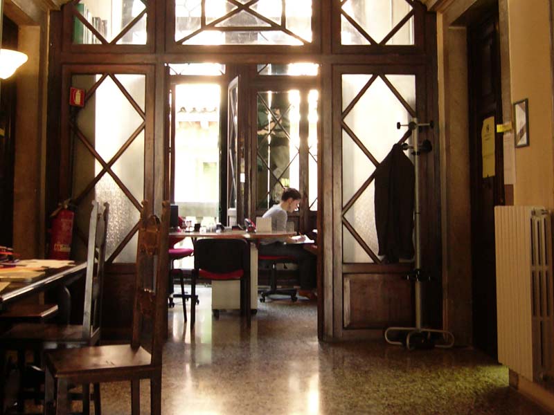 Blick in den Eingangsbereich des Istituto Venezia mit Schreibtischen und einer lernenden Person