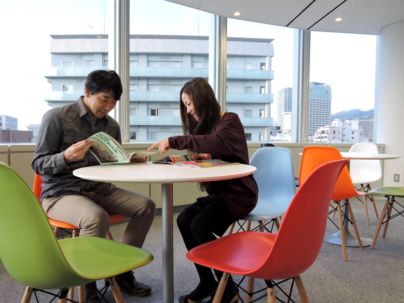 Zwei Personen lernen gemeinsam in der Lounge der Lexis Japan Sprachschule mit Blick auf die Stadt