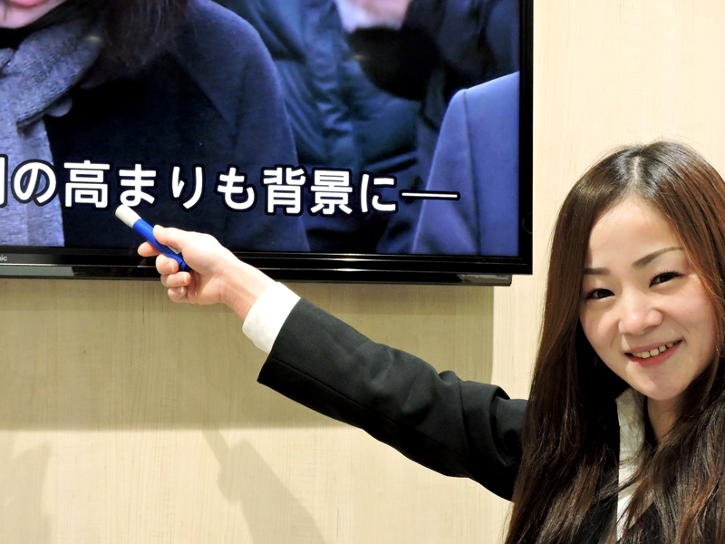 Lehrkraft zeigt auf japanische Schriftzeichen auf einem Bildschirm während des Unterrichts