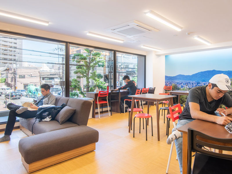 Moderne Lounge mit großen Fenstern und Arbeitsbereichen für Studierende an der Sprachschule