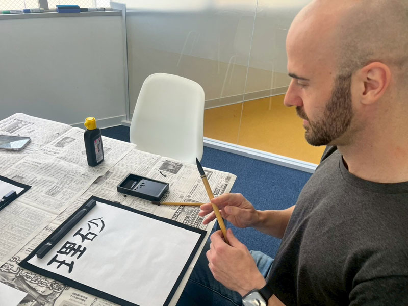 Teilnehmer der LTL Tokio Sprachschule übt japanische Kalligraphie mit Pinsel und Tinte