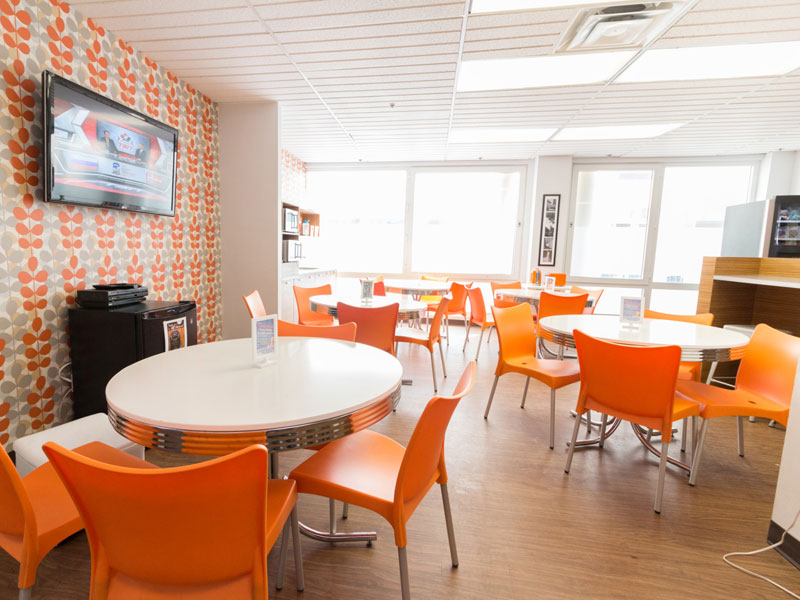 Moderne Lounge mit orangefarbenen Stühlen und grossen Fenstern