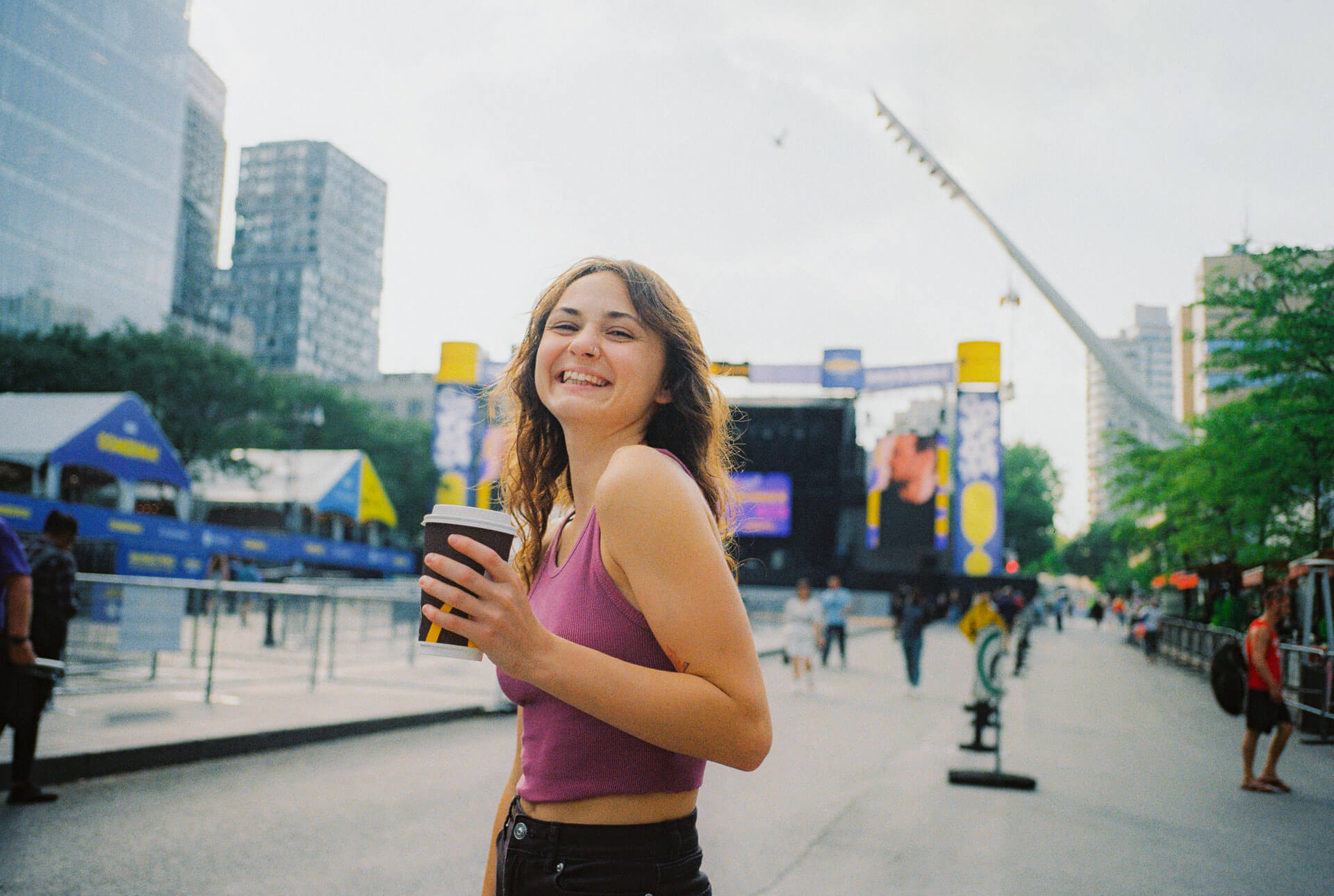 Lachende Person mit Kaffeebecher in der Hand auf einer belebten Strasse in Montreal
