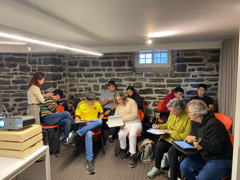 Kleingruppe beim Französischunterricht in einem Raum mit Steinwänden