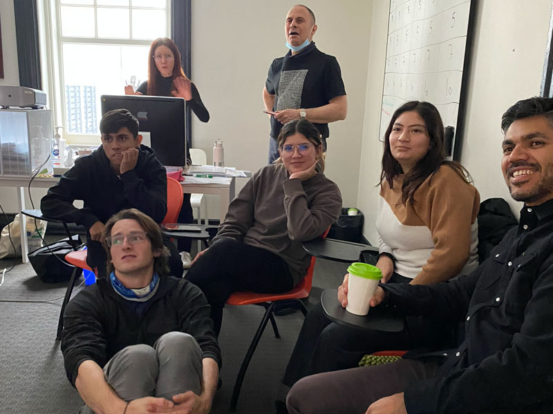 Lernende sitzen in einem Klassenraum und hören aufmerksam der Lehrkraft zu