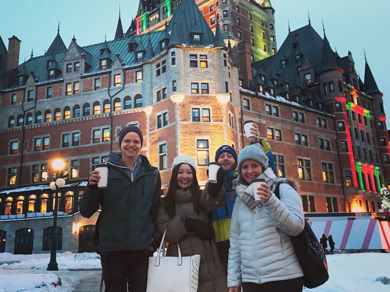 Gruppe von Sprachlernenden steht bei winterlicher Stimmung vor einem beleuchteten historischen Gebäude