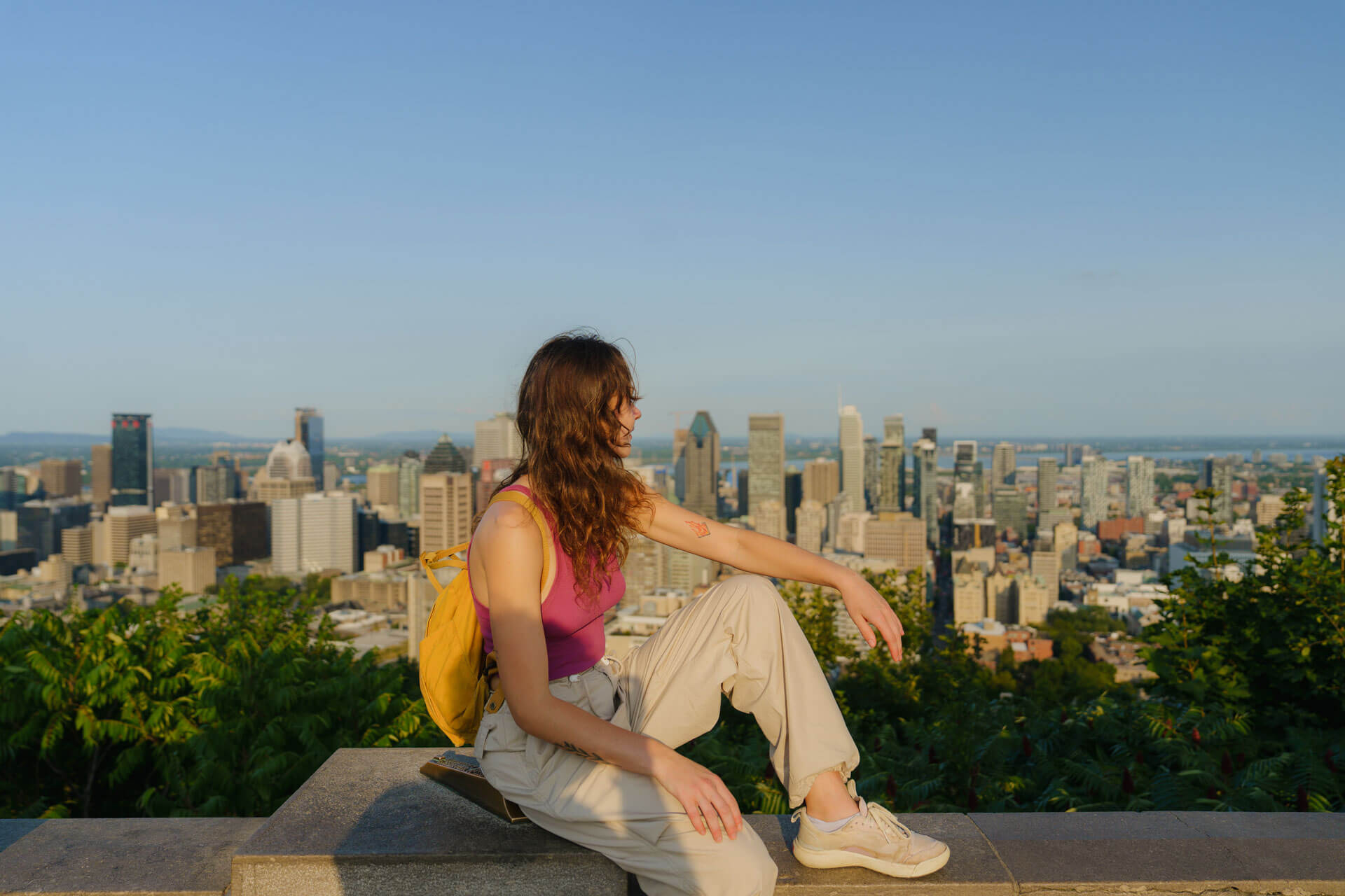Person sitzt mit Blick auf die Skyline von Montréal bei klarem Sommerwetter