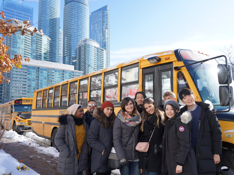 Internationale Sprachschüler vor einem gelben Schulbus in Toronto während eines Ausflugs