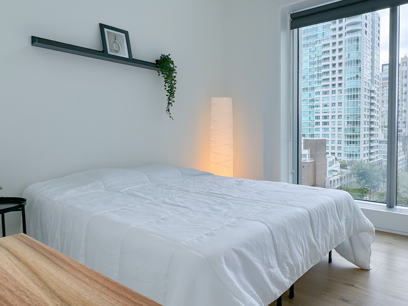 Komfortables Schlafzimmer der CEL Vancouver Unterkunft mit großem Bett und Stadtblick