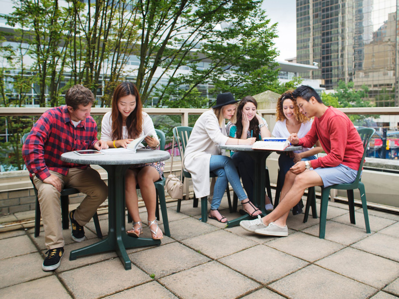 Gruppe internationaler Studierender beim Lernen im Freien auf der Terrasse der Kaplan Sprachschule Vancouver