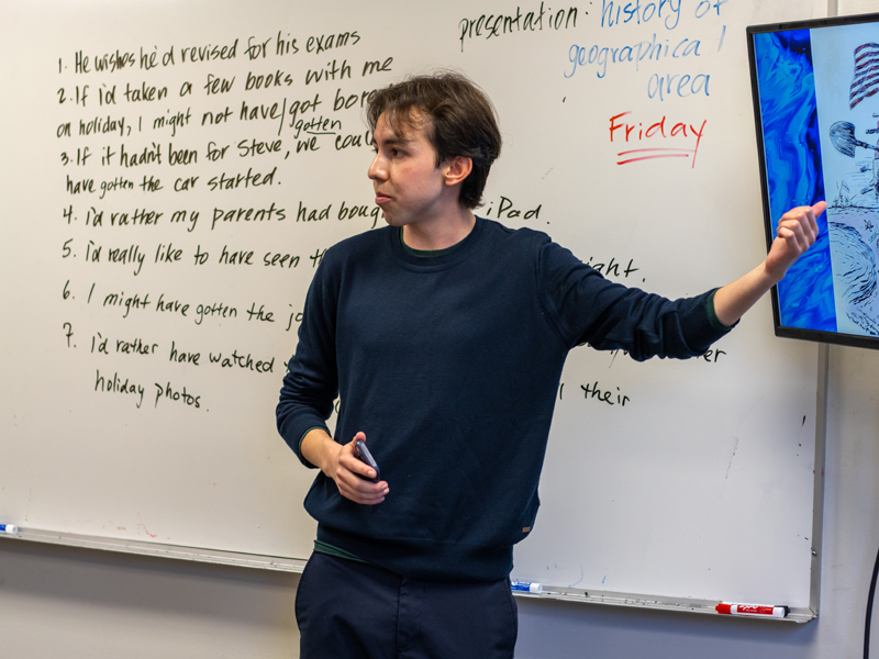 Lehrer erklärt Grammatik und Präsentationstermin an der Tafel – Global Village Victoria