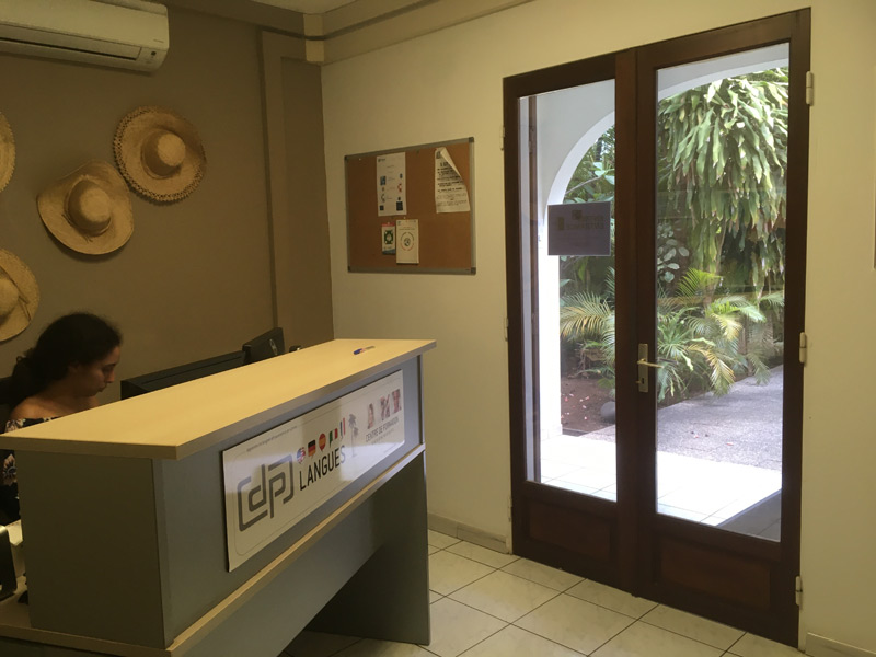 Empfangsbereich der DP Langues Sprachschule mit Schreibtisch und Strohhüten an der Wand