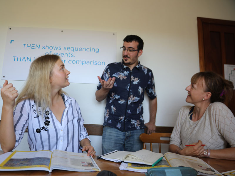 Zwei Teilnehmende im Englischkurs sprechen mit Lehrbuch Life, Sprachkurs mit Fokus auf Dialoge