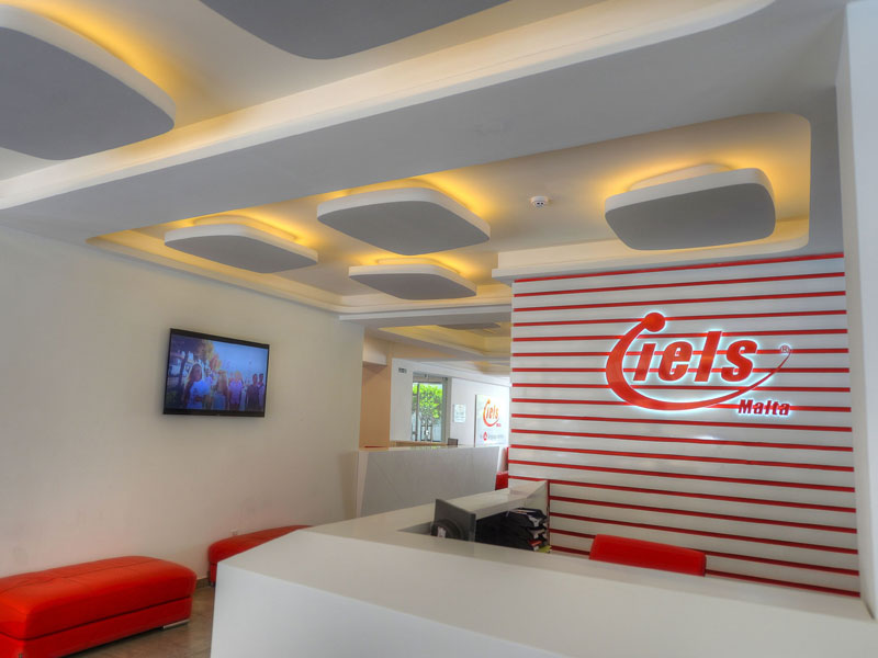 Heller Empfangsbereich der IELS Sprachschule Malta mit moderner Innenarchitektur und roten Akzenten