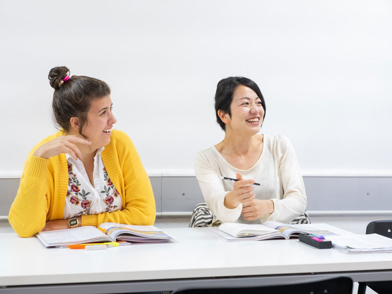 Lernende lachen im Englischunterricht und üben Konversation im Sprachkurs