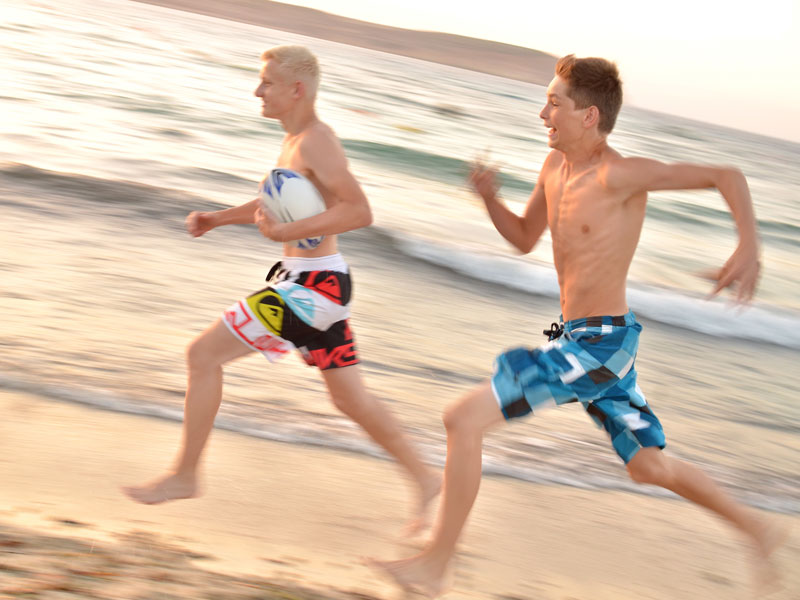 Zwei Jugendliche rennen lachend am Strand mit Ball Englisch lernen auf Malta