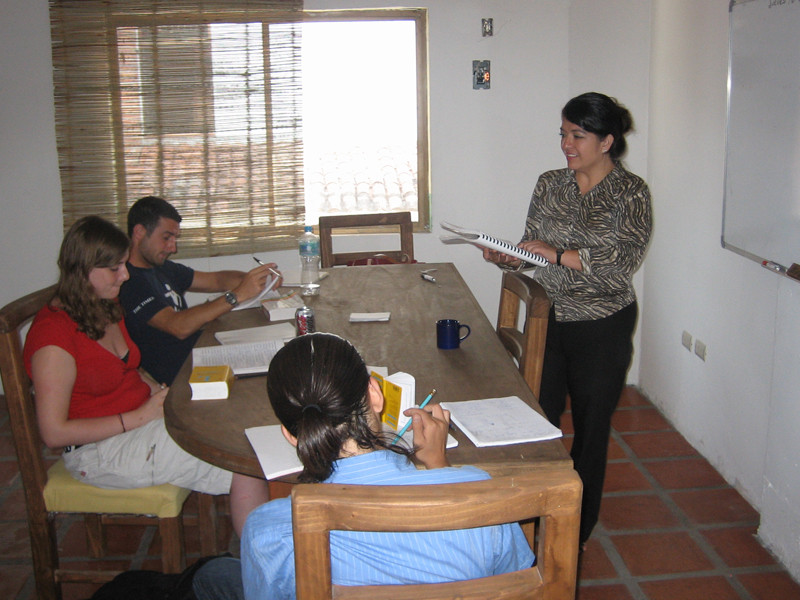 Unterricht im Klassenraum mit Lehrkraft, Schreiben und Hörverstehen im Spanischkurs trainieren