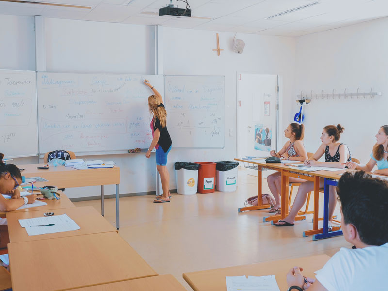 Lehrerin erklärt Grammatik an der Tafel während des Unterrichts mit Jugendlichen
