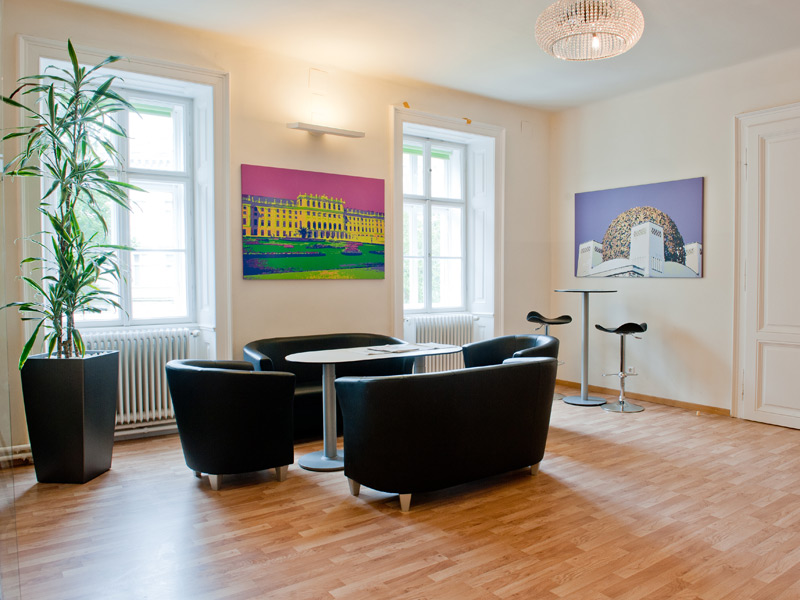 Moderne Lounge der Sprachschule mit Sitzbereich und bunten Wien-Motiven an den Wänden