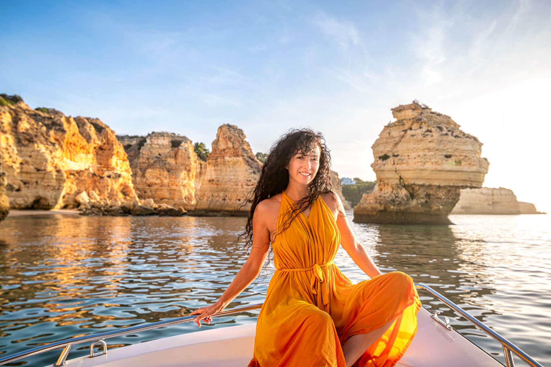 Person genießt eine Bootsfahrt entlang der beeindruckenden Felsenküste der Algarve bei Sonnenuntergang