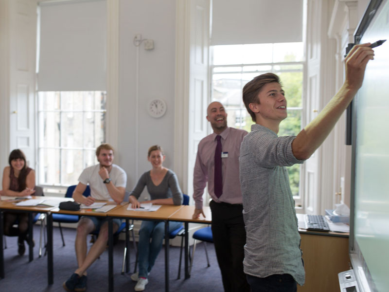 Teilnehmende im Unterricht üben Aussprache und Grammatik mit Lehrkraft