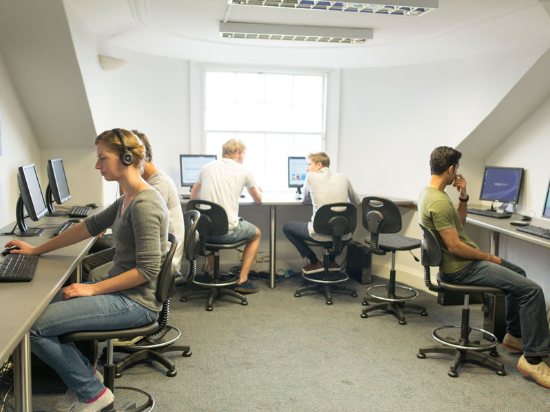 Lernende trainieren Hörverständnis und Schreiben im Computerraum der Sprachschule