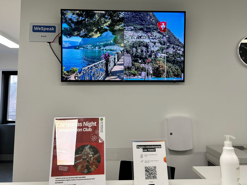 Empfangstresen der Sprachschule StL WeSpeak Lugano mit Bildschirm und Kursinfos